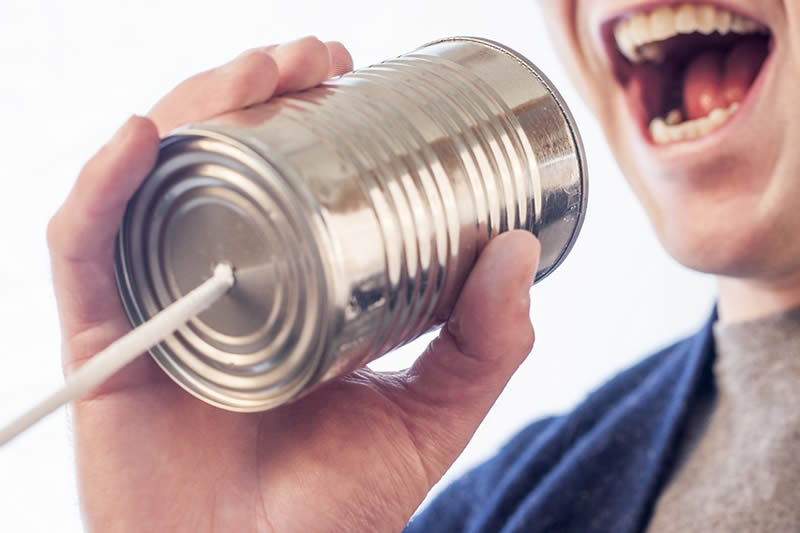 Persona hablando a través de una lata con hilo, simbolizando la comunicación y el análisis de voz con inteligencia artificial